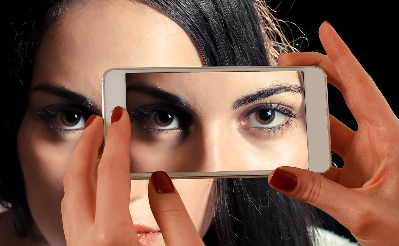 一个女人盯着手机摄像头，眼睛向后反射